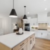 Pheasant Run Sadie Cottage Rambler Detached Villa – Kitchen island with custom cabinet, counter lighting and wood floors