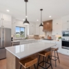 Kitchen with custom cabinets to the ceiling, large island, tile backsplash, and custom stained hood